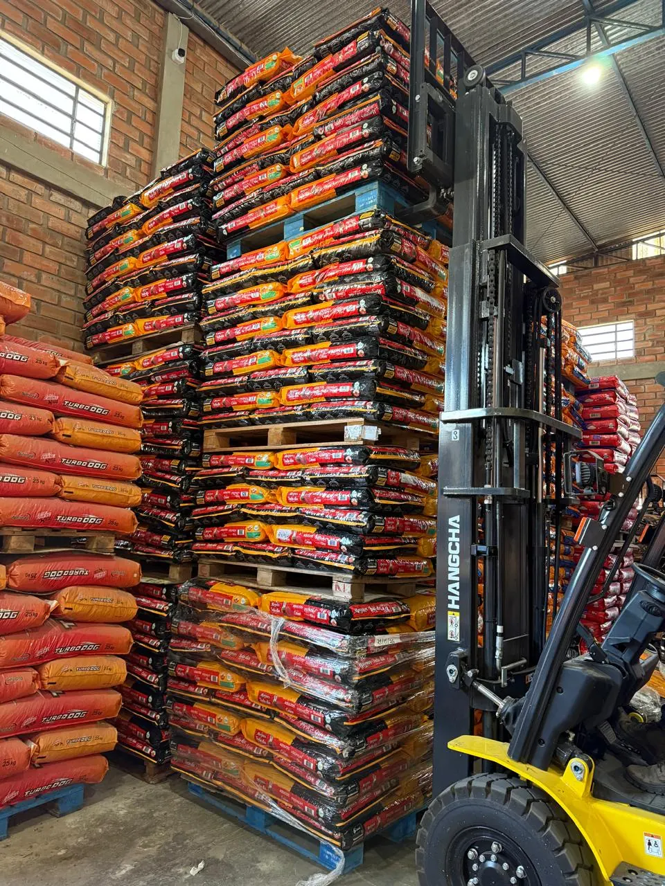 Empilhadeira ao lado de pallets de ração no barracão da Agromar